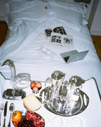 Sukun Vienna pillowcase pair, bone white cotton sateen with a ruffle border, styled lifestyle shot