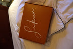 Red box with 'sukun' branding on a white bedspread