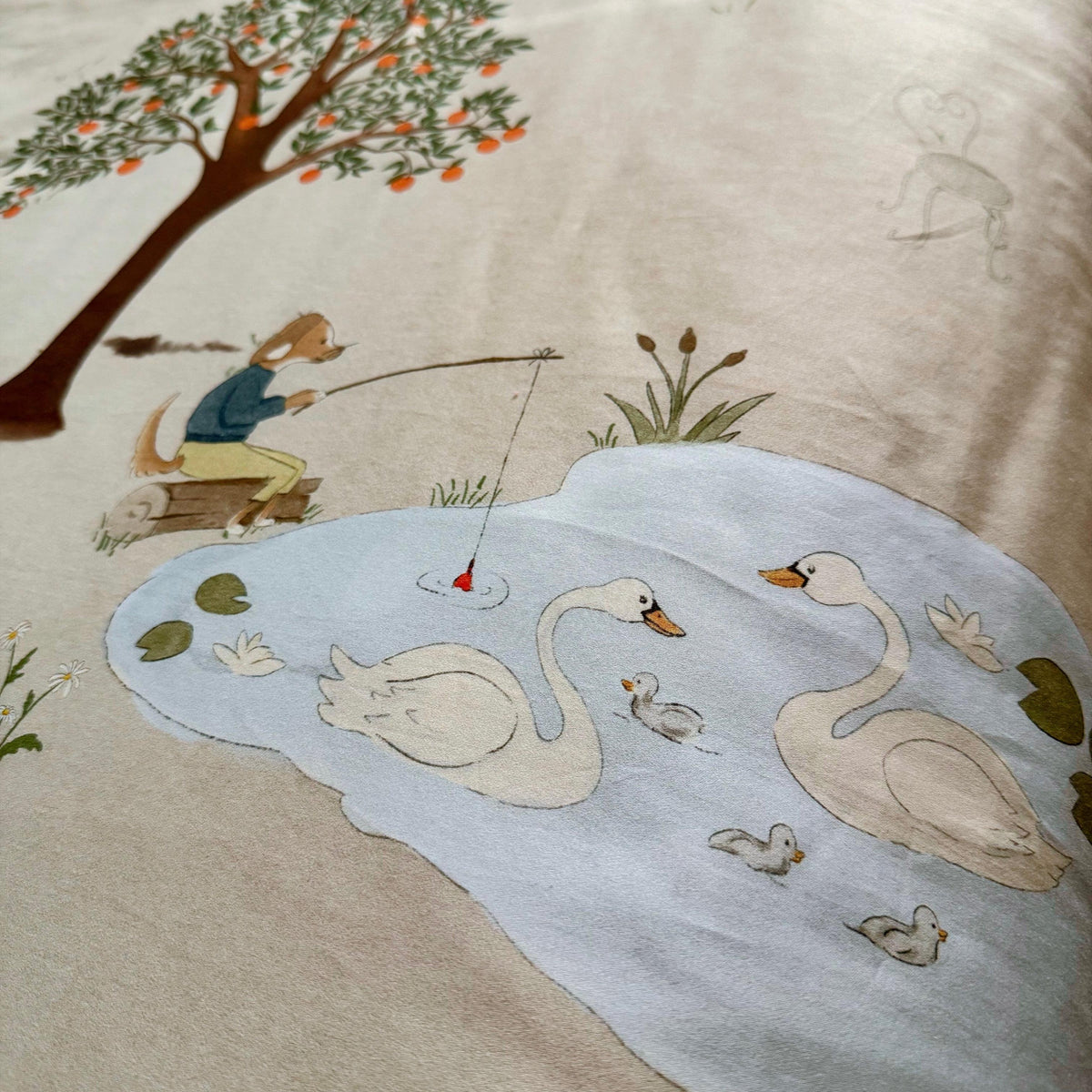illustrated scene with swans, a fisherman, and trees on fabric.- part of a reversible bedding design
