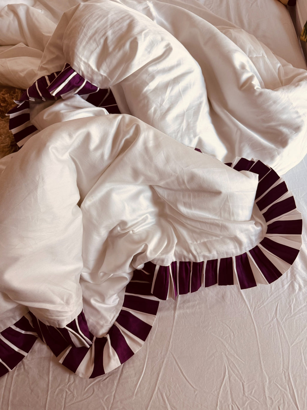 White comforter with purple trim on a bed
